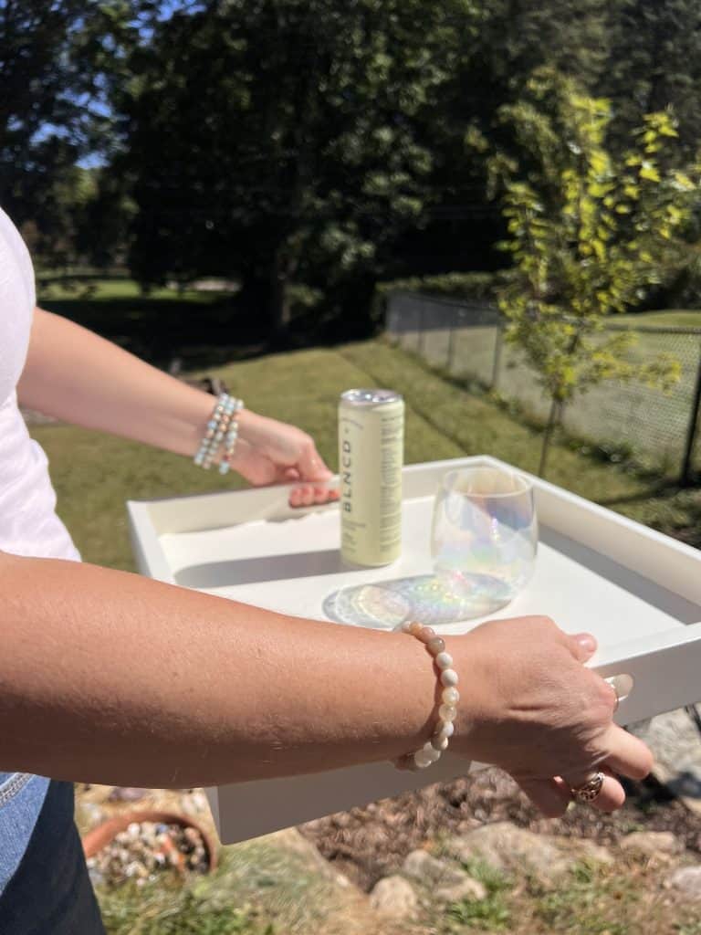 Kate Lily holding tray with BLNCD Naturals THC seltzer and glass in backyard.