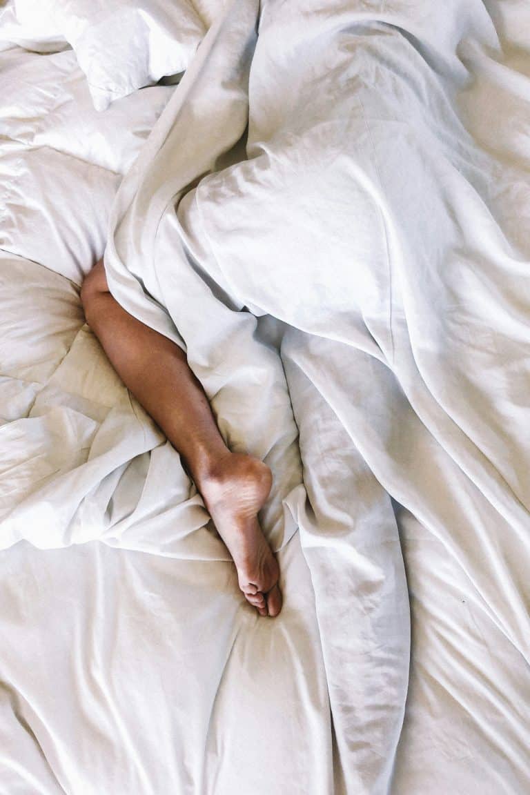 Leg poking out of sheets as someone sleeps