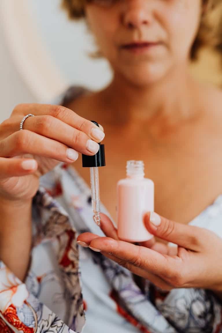 Close-up of a woman applying facial serum using a pipette for a beauty treatment.